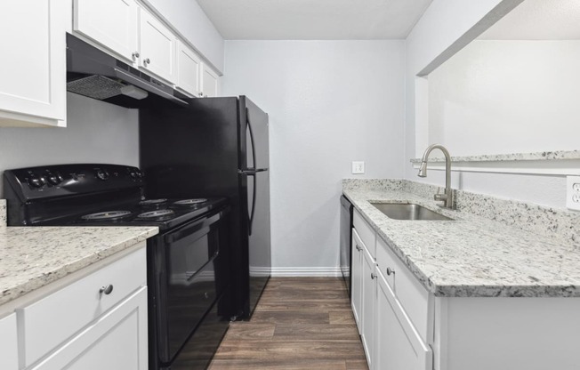 an empty kitchen with white cabinets and a black stove and refrigerator