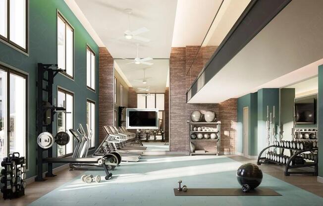Double-height fitness center with strength and cardio equipment, expansive windows, and dedicated space for training, conditioning, and recovery.
