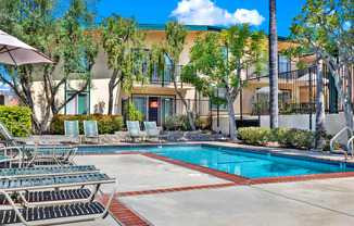 a swimming pool with chairs and a building in the background at Camino de Oro Apartments, California, 90505