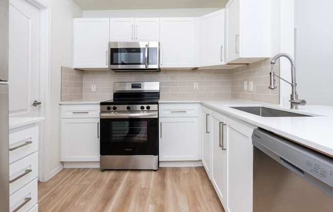 a white kitchen with stainless steel appliances and white cabinets