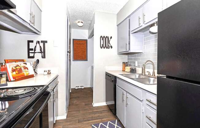 A kitchen with a black refrigerator and a white counter top.