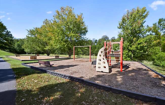 A playground with a red swing set and a white slide.
