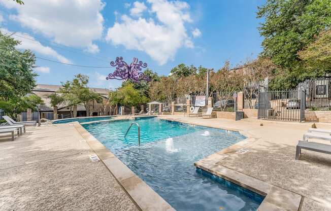 a swimming pool with a fountain and a fence with trees