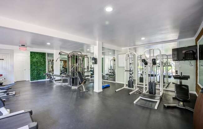 Fitness center in Fusion Warner Center apartments in Woodland Hills with weight training machines facing large mirror wall.