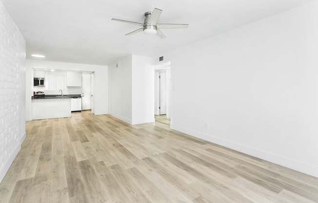 A room with a ceiling fan and wooden flooring.