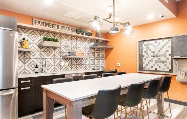 a kitchen with a large white table and black and white tiles on the wall