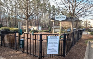 A sign in front of a fence that says Dog Park Rules.