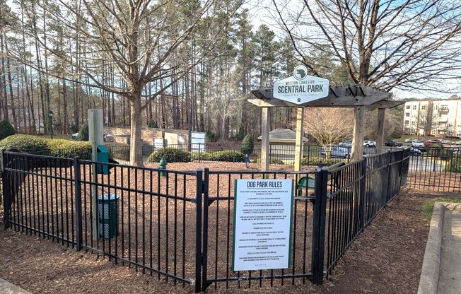 A sign in front of a fence that says Dog Park Rules.