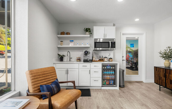 a living room with a chair and a kitchen with a microwave