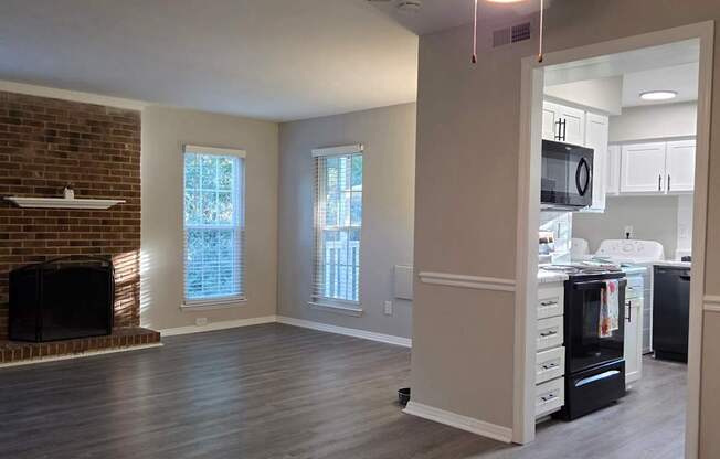 A room with a ceiling fan and a brick fireplace.