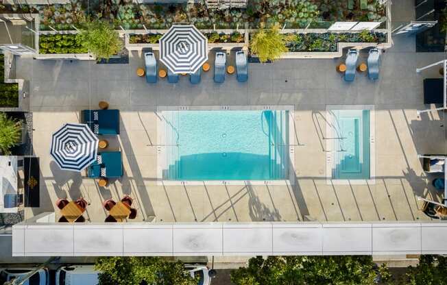 an aerial view of a pool and patio with umbrellas