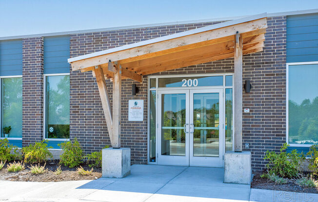 The front of a building with a wooden canopy and a sign that reads at Lofts at Fox Ridge, Raymore, MO