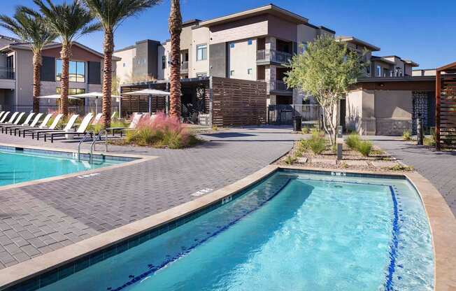 A swimming pool surrounded by palm trees and lounge chairs.