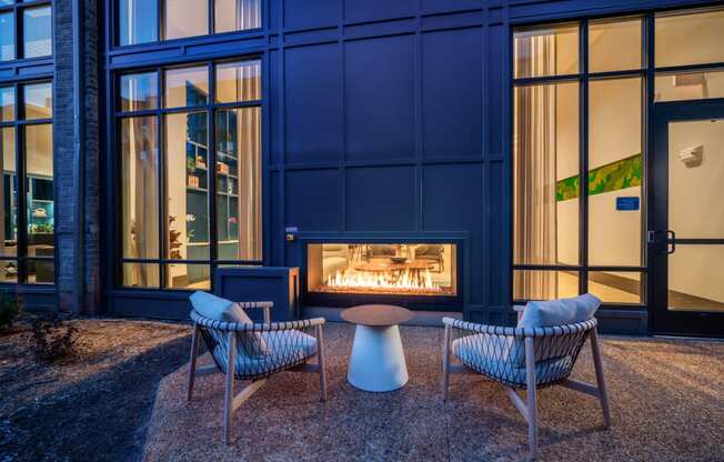 a fireplace in front of a blue building with chairs and a table at Preston Ridge, Cary, NC