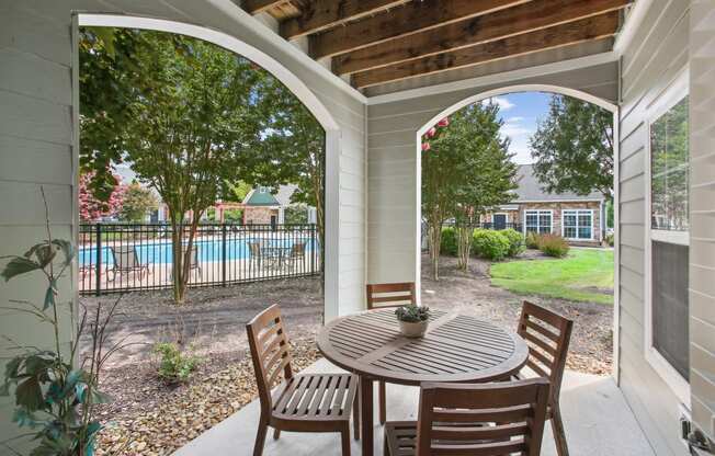 a patio with a table and chairs and a swimming pool