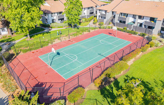 A basketball court surrounded by a fence and trees.