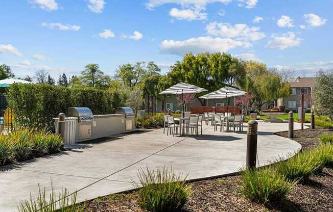 A park with a table and chairs and a trash can.