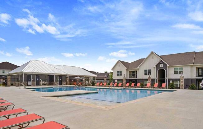 A swimming pool surrounded by red sun loungers and a building in the background.