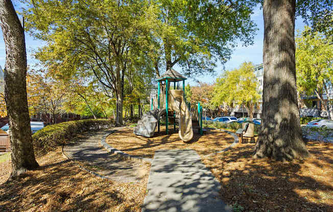 Flatiron West Trade Apartments playground with slides, mulch and a bench.