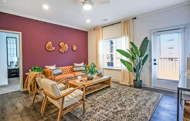 A living room with a sofa, chair, and potted plants.