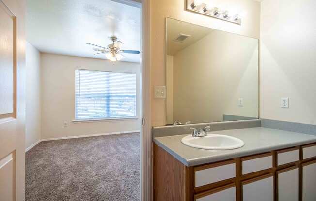 Bathroom connected to room with single sink, top light, big mirror