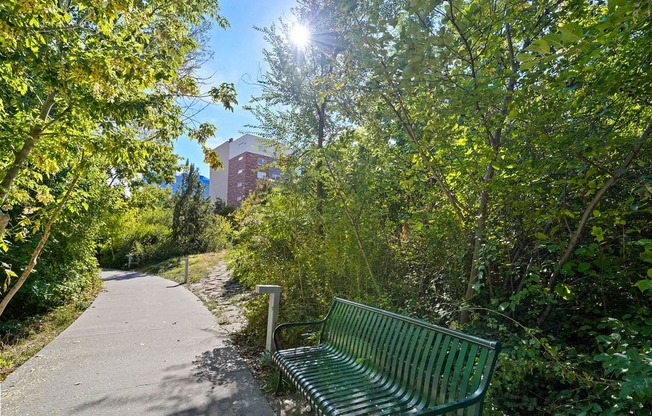 a green park bench sitting next to a sidewalk