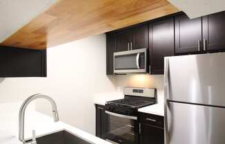 a kitchen with stainless steel appliances and Expresso Colored cabinets