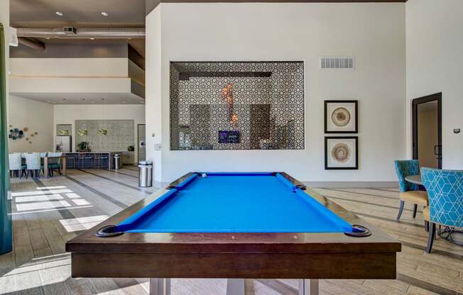 A pool table in the middle of a room with a blue cloth.