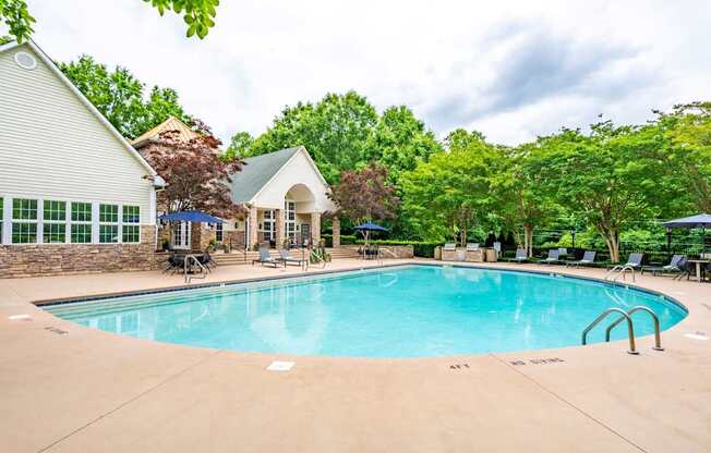 A large swimming pool in front of a house with a pool house.