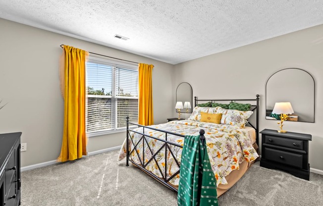A bedroom with a bed, dresser, and window with yellow curtains.