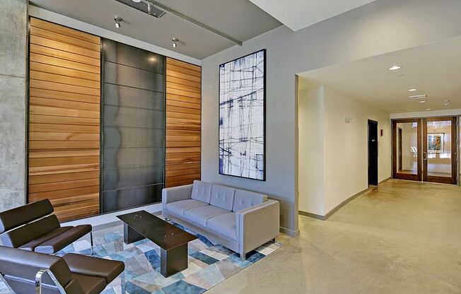 Lobby with laminate flooring, tall ceiling and art. Furnished with couch, 2 chairs and coffee table.at 19th & Mercer, Seattle, WA