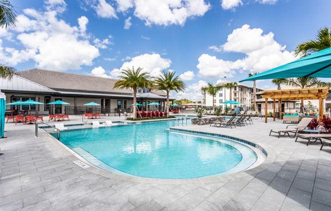 exterior pool with patio furniture and palm trees on sunny day