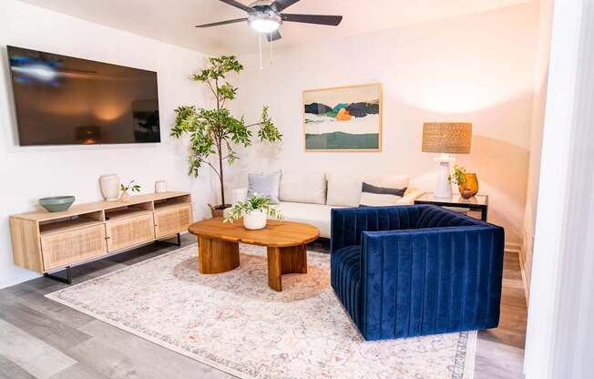 A living room with a blue velvet sofa and a wooden coffee table.