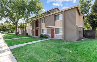A row of townhouses with green lawns in front.