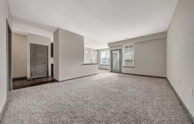 the living room and kitchen of a new home with white walls and carpet