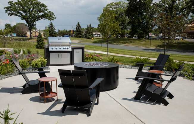 a fire pit and seating area on a patio with an outdoor kitchen in the background