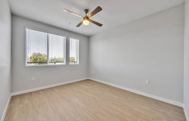 A room with a ceiling fan and a window with blinds.