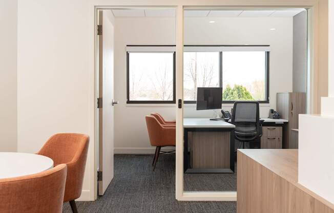 A room with a desk, chairs and a computer.