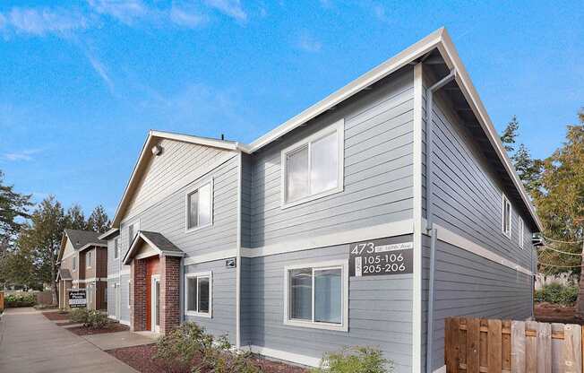 A grey house with a red door and a sign on the front.