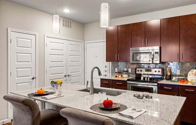 A kitchen with a table and chairs in the foreground and a microwave above the stove. at Bridge at Southpark Meadows, Austin, TX, 78748