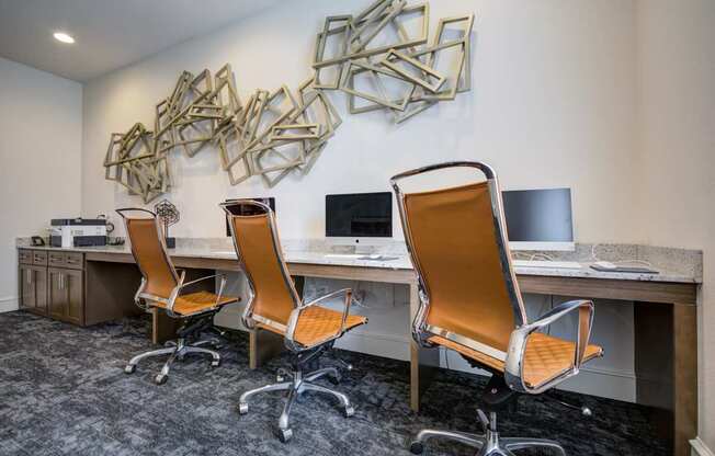 Three chairs are in front of a desk with a computer.