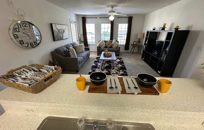 A kitchen with a clock on the wall and a dining table set for two.