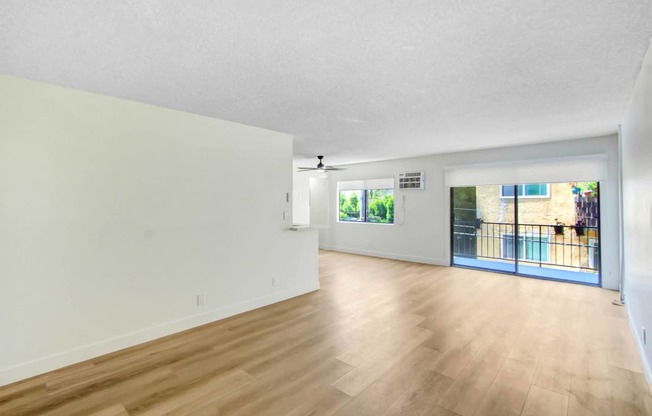 the living room and dining room of an apartment with wood floors and white walls