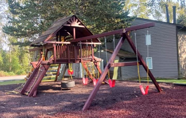 A wooden swing set in a backyard.