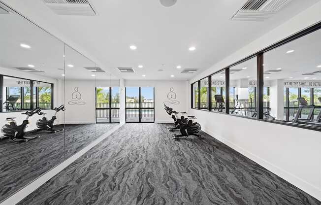 A gym with exercise machines and windows in a building