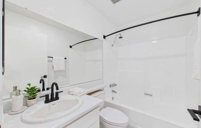 A white bathroom with a toilet, sink, and bathtub.