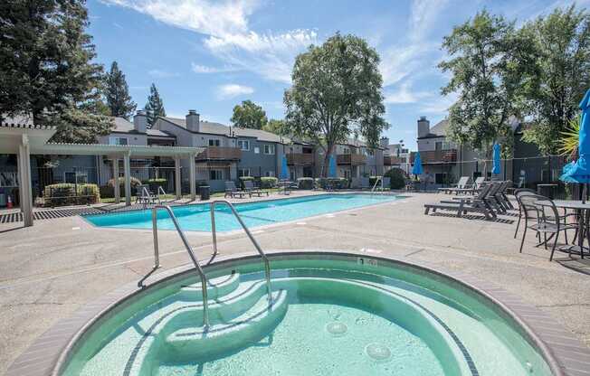 A hot tub sits in the middle of a pool area with a building in the background at Sierra Glen Apartments, California, 95621