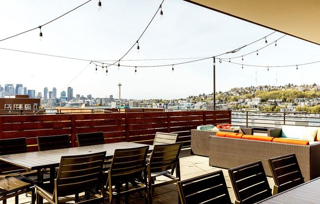 a roof deck with tables and chairs and a view of the city