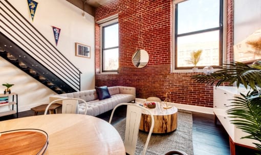 a living room with two couches and a table and a brick wall