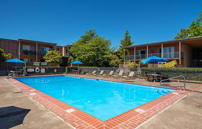 outdoor pool with seating around and blue umbrellas over tables.